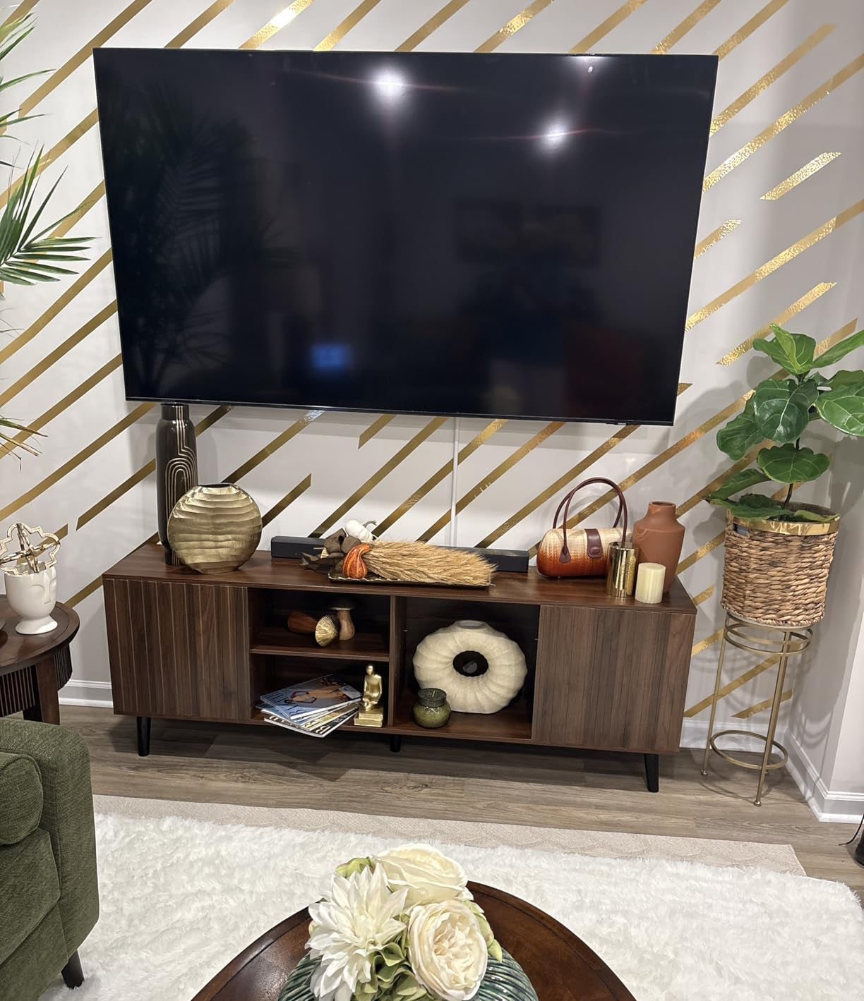 TV mounted on a wooden stand with decorative items against a geometric wall pattern.